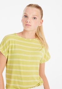 T-shirt a righe verdi con vestibilità morbida, scollatura rotonda e maniche corte; il tessuto appare soffice e leggero con righe orizzontali bianche.