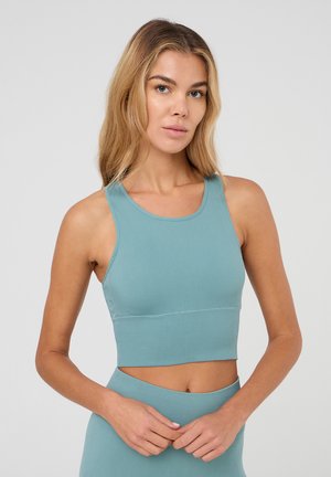 Cropped top a coste color turchese chiaro con scollo rotondo e spalline larghe. Il tessuto sembra elastico, con una silhouette aderente, bordi senza cuciture e senza decorazioni.