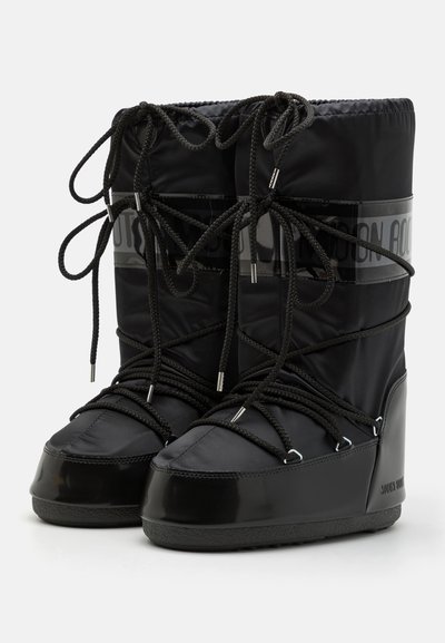 Bottes noires imperméables avec un haut rembourré et une partie inférieure en caoutchouc brillant. Comprend une surface texturée, des lacets ajustables et des accents de marque en gris.