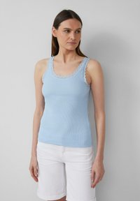 Lichtblauw ribgebreid tanktop met een scalloped kanten rand langs de halslijn en schouderbandjes, gecombineerd met witte shorts. Gladde textuur.