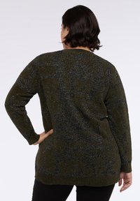 Maglione verde lavorato a maglia con un motivo testurizzato, caratterizzato da accenti in filo argentato. Maniche lunghe e design dalla vestibilità rilassata.