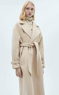 Beige villakangastakki, jossa on vyötärölle sidottava vyö, suuret kaulukset ja käännetyt hihat. Silkkinen pinta ja pitkä siluetti, jossa on sivutaskut.