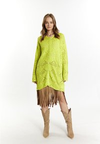 Neon grön virkade klänning med geometriska utskärningar och fransar i nederkanten. Kombinerad med ljusbruna cowboystövlar med en strukturerad design.