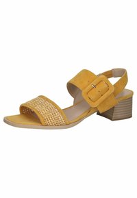 Sandal in suede giallo con cinturino intrecciato, punta aperta e chiusura con fibbia. Presenta un tacco basso e impilato e una suola liscia.
