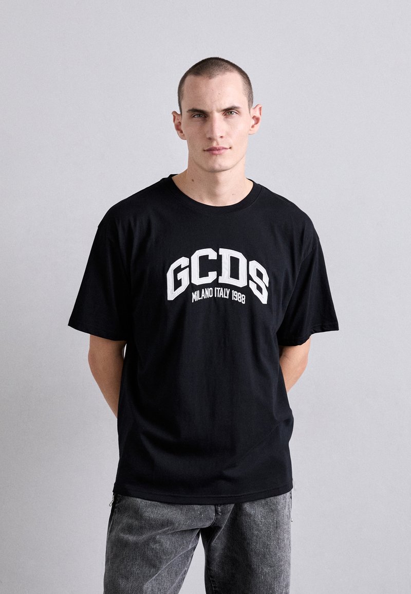 T-shirt nera in cotone con stampa bianca "GCDS Milano Italia 1988", vestibilità rilassata con maniche corte e scollatura a girocollo.
