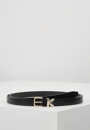 Czarny skórzany pasek ze złotą klamrą i dekoracyjnym złotym motywem liścia, zwinięty na białej powierzchni.