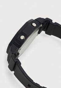 Ceas digital negru cu o curea din cauciuc texturată, butoane din metal argintiu și spate din oțel inoxidabil.