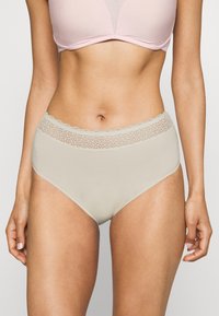 High-waisted beige panties with a lace trim at the waist, featuring a smooth texture and simple design. No visible patterns or hardware.