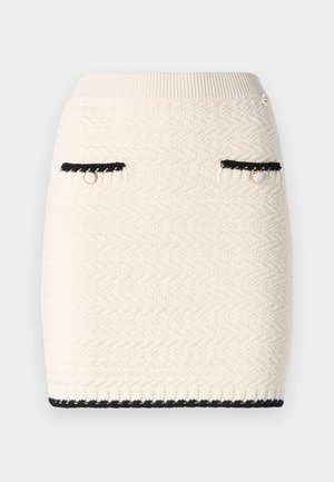 Knit mini sijonas kreminės spalvos su tekstūruotu zigzags raštu, akcentuotas juodos spalvos apdailomis aplink kišenes ir hemą, bei auksinės spalvos detalėmis.