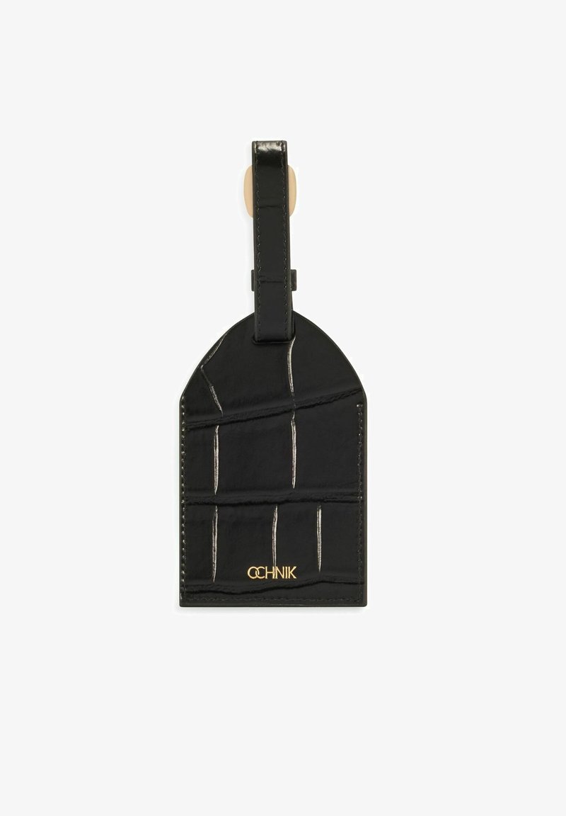 Czarny skórzany identyfikator do bagażu z fakturowanym wzorem, wyposażony w pętlę do zawieszenia i złote logo "OCHNIK" na dole.