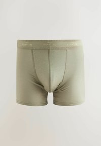 Olíva zöld boxer alsónadrág puha anyagból, rugalmas derékrésszel, aranybetűs felirattal. Kialakítása kényelmes, szoros fazonú, közepes hosszúságú lábszárral.