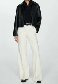 Sort læder cropped jakke, ribbet sort top, hvide vidde bukser, sort bælte, blanke sorte sko, der har et slankt, moderne design.