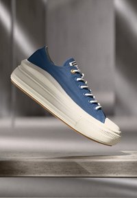 Baskets en caoutchouc bleu avec un dessus texturé et une semelle intermédiaire blanche, présentant des lacets ronds et une semelle en gomme, affichant un design moderne.