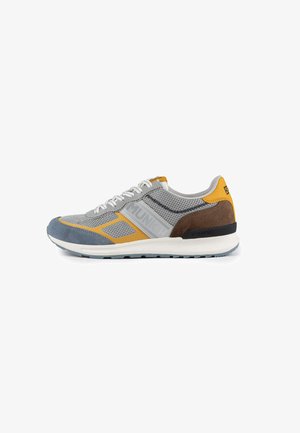Scarpa sportiva grigia con tomaia in mesh e dettagli gialli, marroni e blu, lacci bianchi e suola intermedia testurizzata per supporto.
