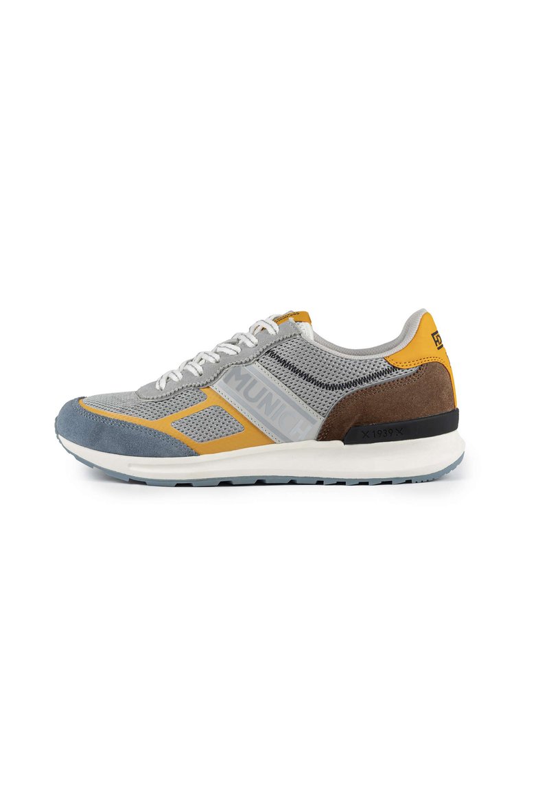 Scarpa sportiva grigia con tomaia in mesh e dettagli gialli, marroni e blu, lacci bianchi e suola intermedia testurizzata per supporto.