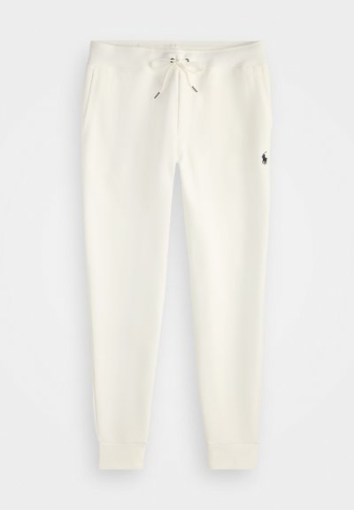 Białe spodnie dresowe wykonane z miękkiego materiału, z elastycznym paskiem ze sznurkiem, bocznymi kieszeniami i małym czarnym logo na dolnej części nogawki.