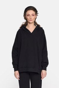 Czarna bluza z kapturem o luźnym kroju, wykonana z miękkiego materiału. Posiada dekolt w kształcie litery V, opadające ramiona oraz ściągacze na rękawach.
