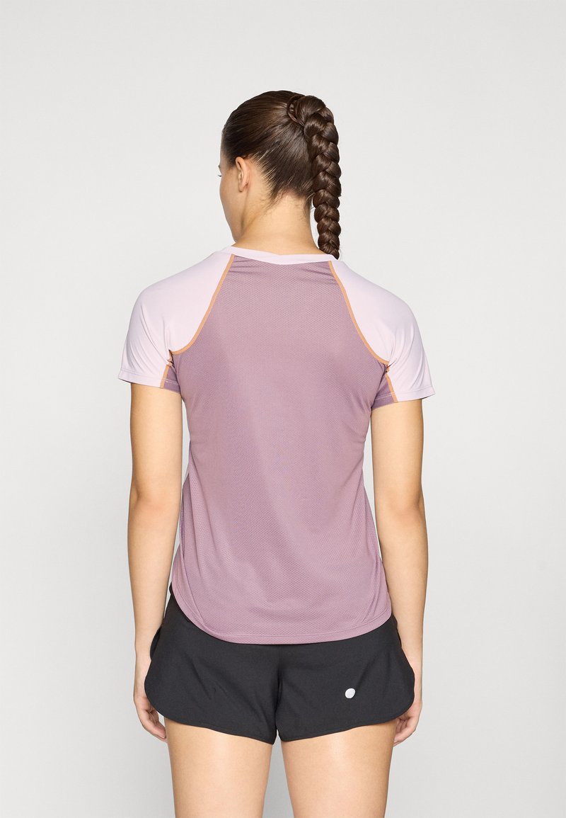 Sportliches T-Shirt mit kurzen Ärmeln in Lavendel mit hellrosa Schultern, Netzstruktur und kontrastierenden Nähten. Kombiniert mit schwarzen Shorts.