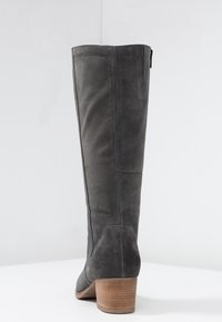 Szare zamszowe bootsy sięgające kolan, z lekko zaokrąglonym noskiem, teksturowaną powierzchnią i średnim brązowym słupkowym obcasem. Posiadają zamek błyskawiczny po boku.