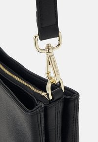Borsa a mano in pelle nera con finitura testurizzata. Presenta una cerniera e accessori in tono oro, oltre a una tracolla rimovibile per una maggiore versatilità.