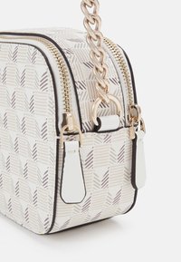 Pravokutna crossbody torba od uzorkastog materijala u bijeloj, bež i smeđoj boji. Ima zlatne detalje, dvostruke patentne zatvarače i lančanu traku.