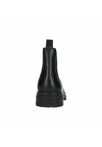 Zwarte leren enkelboots met een chunky zool, elastische zijpanelen en een trekstijl. Textuurafwerking met een strakke silhouet.