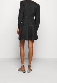 Musta, polvipituinen mekko puffi-hihoilla ja kerroksellisella helmalla. Sisältää kontrastivärjäyksen ja yhteensopivan vyön. Yhdistetty zebrakuvioitujen korkokenkien kanssa.