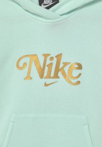 Mintgrön hoodie gjord av mjukt material, med en guldig "Nike"-logotyp och en känguruficka framtill. Hoodien har en dragsnodd i huvan.