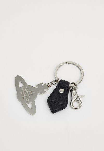 Keychain featuring a silver metal tag shaped like a planet with a tree, attached to a black textured leather accent and a silver clasp.
