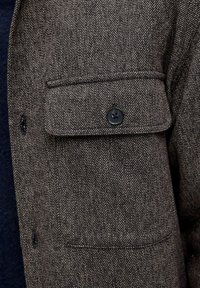 Pruun kalasabamustriga kangast särk rinnatasku ja musta nööbiga. Omab tekstuurset mustrit ja veidi karedat viimistlust.