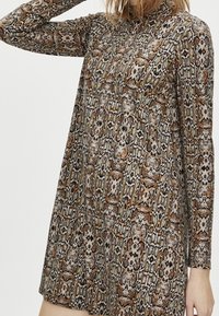 Robe à manches longues avec un motif serpent dans des teintes de brun, beige et noir, dotée d'un col haut et d'une coupe décontractée.