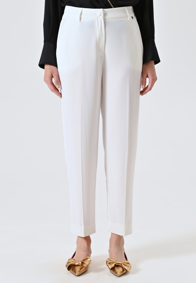 Witte op maat gemaakte broek met een gladde stof, rechte snit en cropped zoom. Gecombineerd met flats met gouden strikdetails voor contrast.