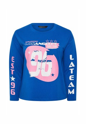 Camicia blu a maniche lunghe con grafica "96" rosa e bianca, "LOS ANGELES First Team," stelle e testo "EST 96" sulla manica sinistra, "LA TEAM" sulla manica destra.