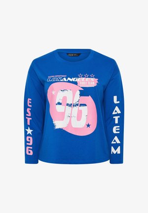 Camicia blu a maniche lunghe con grafica "96" rosa e bianca, "LOS ANGELES First Team," stelle e testo "EST 96" sulla manica sinistra, "LA TEAM" sulla manica destra.