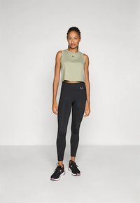 Kerge oliiviroheline lühike tank top logo ja mustad retuusid, mustad sportlikud jalanõud roosa aktsendiga. Sile kangas ja istuv disain.