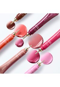 Zeven tubes vloeibare blush in verschillende tinten, waaronder roze, koraal en rood, met gouden accenten, naast bijpassende ronde kleurstalen.