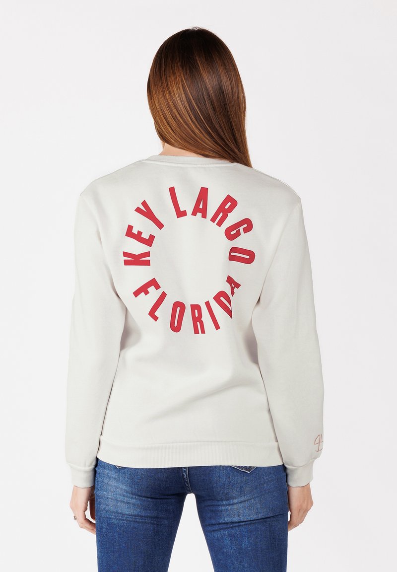 Felpa grigia chiara con "KEY LARGO FLORIDA" stampato in bold rosso sul retro. Il tessuto è morbido; il design ha una vestibilità rilassata e polsini a coste.