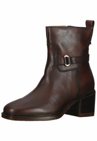 Botín de cuero marrón hasta el tobillo con puntera cuadrada, acento de hebilla plateada en la correa y tacón apilado. Textura suave con detalles de costura.