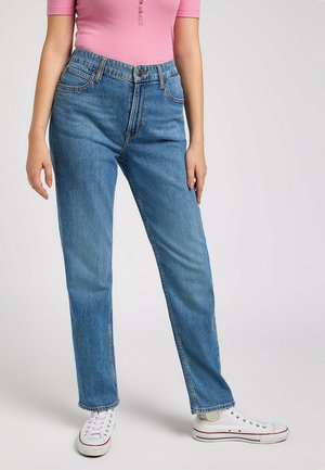 Jeans in denim celeste con taglio a gamba dritta, cinque tasche e chiusura a bottone. Abbinati a scarpe da ginnastica bianche e a un top rosa a costine.