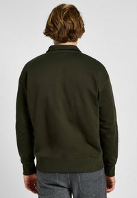 Felpa verde oliva con orlo e polsini a costine, caratterizzata da un design semplice e una consistenza morbida, vista da dietro.
