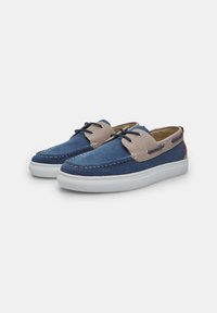 Scarpe in tela blu con dettagli beige, punta rotonda, suola in gomma bianca e cuciture a contrasto. Presentano chiusura con lacci e occhielli laterali.