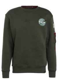 Felpa verde oliva con collo a giro, logo NASA sul davanti, patch della bandiera sulla manica e tasca con zip sul braccio. Tessuto morbido, polsini a coste.