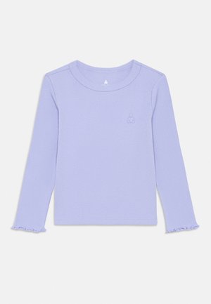 Camiseta de manga larga color lila con textura acanalada y cuello redondo, con un pequeño logo bordado en el pecho izquierdo, mostrada extendida sobre un fondo blanco.