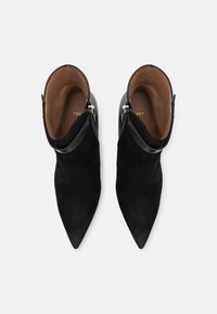 Czarne zamszowe botki za kostkę z wysmuklonymi noskami, kontrastującą czarną skórzaną lamówką, bocznymi zamkami błyskawicznymi oraz gładkim, jasnobrązowym wnętrzem.