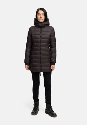Black puffer coat with a high collar and hood, featuring a front zipper and ribbed cuffs. Worn over black skinny jeans and boots.