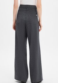 Wide-leg pants in a textured dark gray fabric, featuring a high waist and two back pockets. Small logo accent on the right side.
