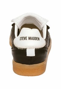 Sneaker in pelle nera con accenti bianchi, tacco texturizzato e suola in gomma color caramello. Nome del marchio "STEVE MADDEN" stampato sul tacco.
