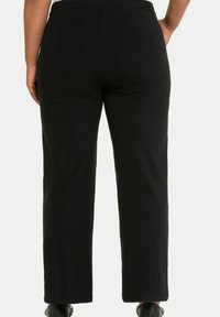 Pantaloni neri con vita elasticizzata, dalla vestibilità dritta e ampia. Realizzati in tessuto morbido, presentano una texture liscia e senza motivi o accessori in evidenza.