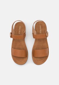 Brown leather sandals with two wide straps. Adjustable ankle buckle. Smooth upper texture and cushioned insole. Stitched detailing.