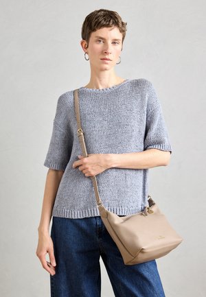 Világosszürke kötött pulóver rövid ujjakkal, laza kék farmernadrággal és bézs bőr válltáskával, amely cipzárral záródik.